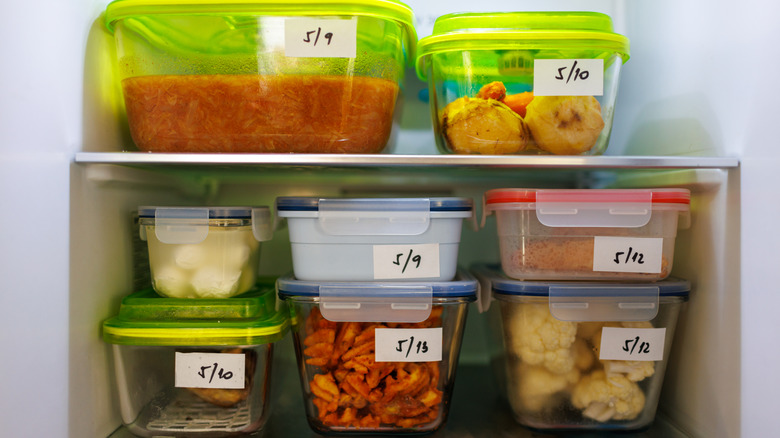 Varioues foods in clear containers with dated labels stacked in a refridgerator