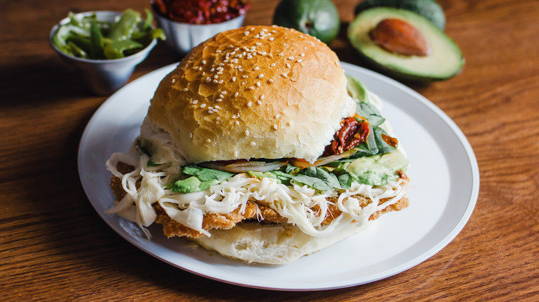 cemita milanesa on a plate with condiments in background