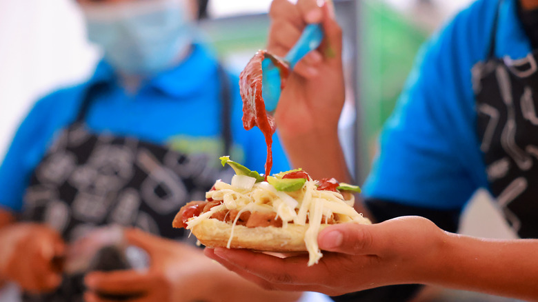 vendor putting sauce on cemita sandwich