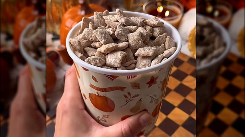 A hand holding a container of apple cider muddy buddies