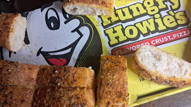A portion of breadsticks on top of a cardboard Hungry Howie's container