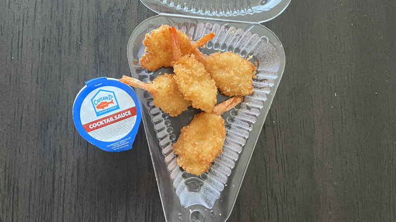 Captain D's 5-piece butterfly shrimp in a to-go container with a cup of sauce