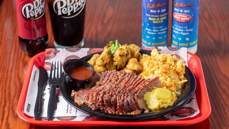 BBQ platter with brisket, sides, and Dr. Pepper on red tray