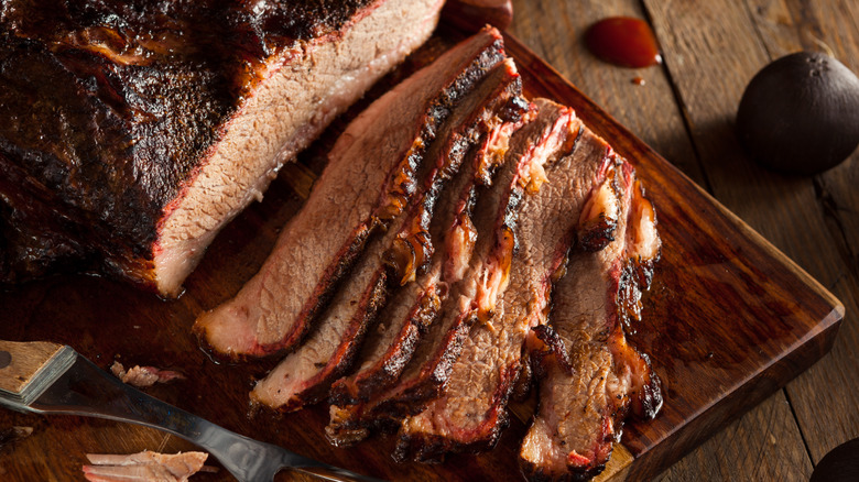 Slices of brisket next to full cut on wooden board