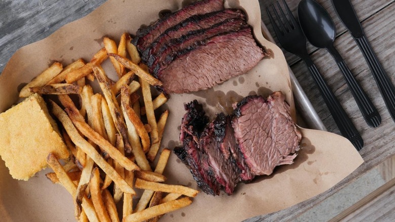 Slices of brisket with fries on brown paper
