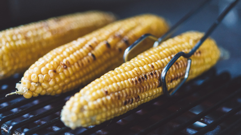 corn on the cob being flipped on the grill