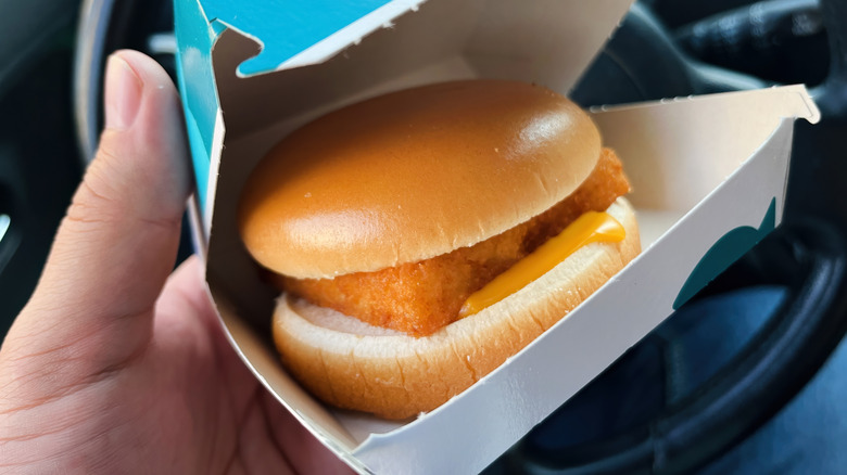 A person holds a McDonald's Filet-o-Fish in a car
