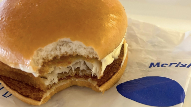 A close-up of a McFish with a bite taken out on branded paper