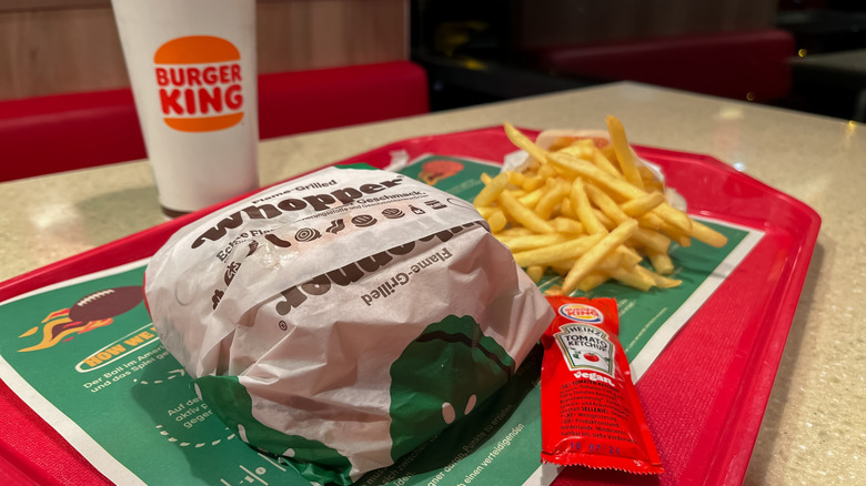 A Burger King Meal with a whopper, fries, and a ketchup packet on a red tray