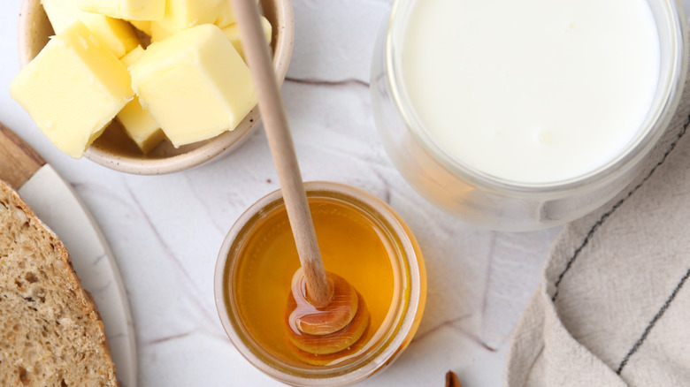 Ingredients to make honey butter French toast like honey, butter in bowls on a table.