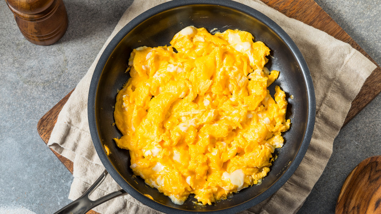 A pan of scrambled eggs is on a table.