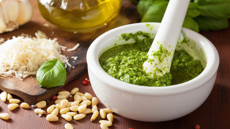A mortar and pestle has pesto in the bowl.
