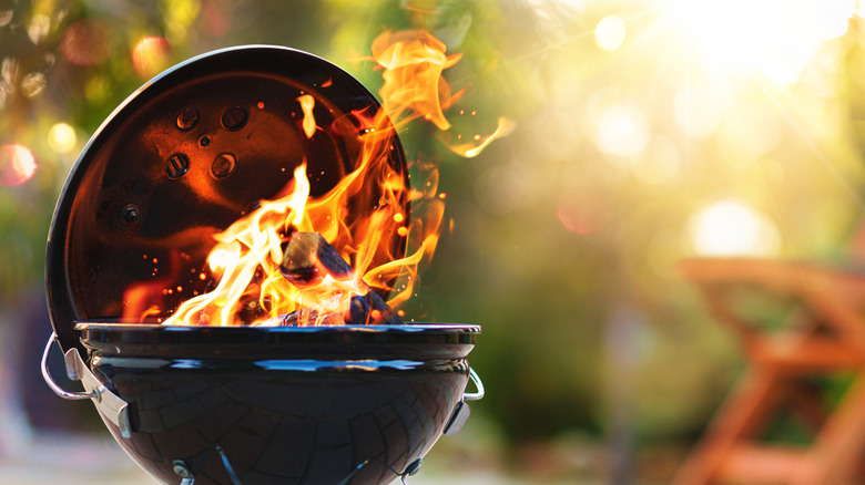 Small black barbecue with flames licking up around wood inside