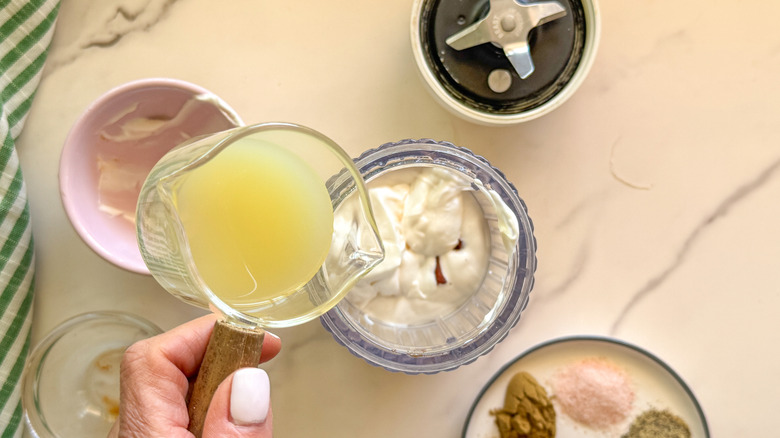 hand adding lime juice to blender