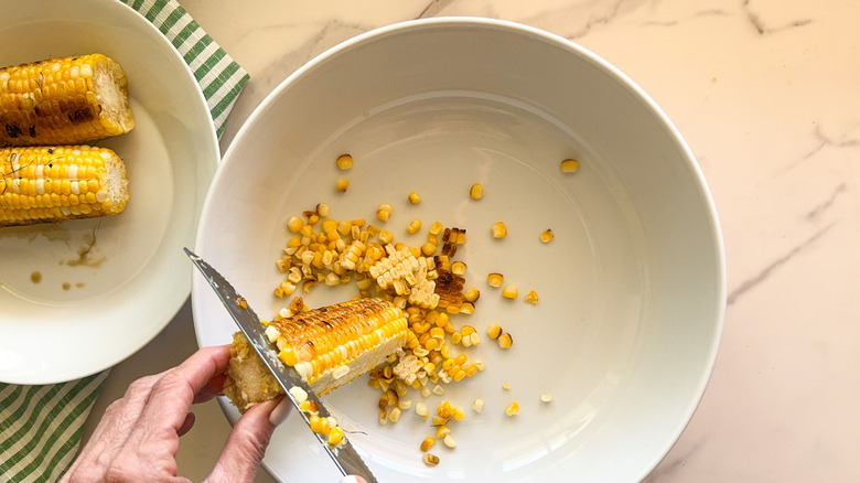 hand cutting off corn kernels