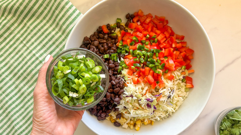hand adding scallions to bowl
