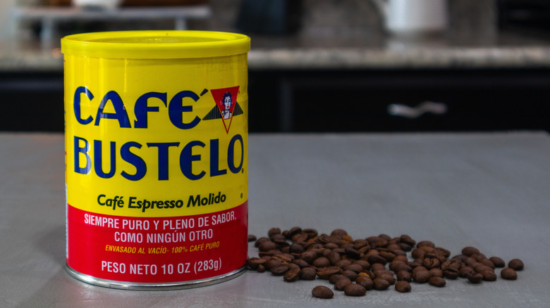 Can of Café Bustelo next to pile of coffee beans on grey countertop