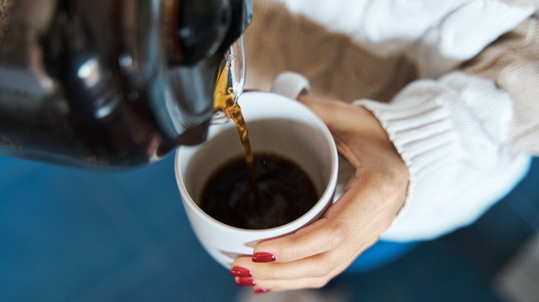 Close-up of woman pouring coffee into a mug