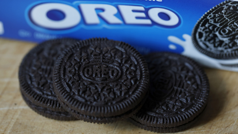 Three Oreos on a table in front of an Oreo package
