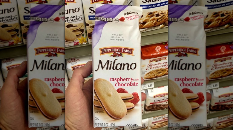 Hand holding a bag of Raspberry Chocolate Milanos in a grocery store aisle