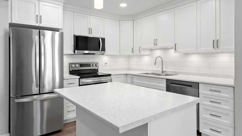 A kitchen island with a glossy white marble countertop with deep gray veining