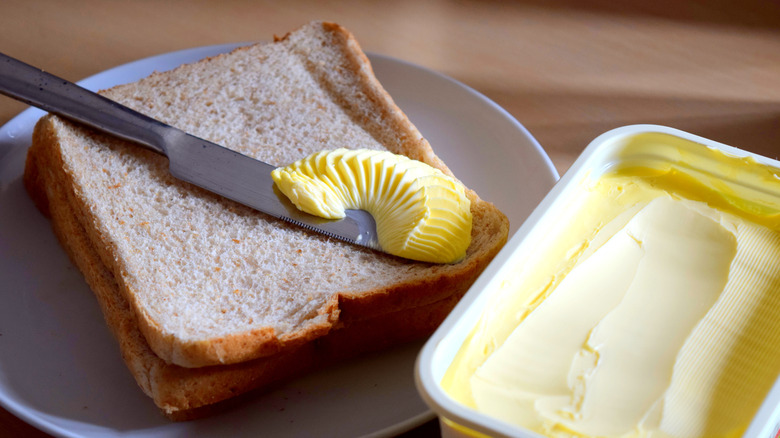 butter on knife with two slices of bread