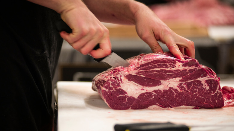 Butcher slicing into a chuck roll