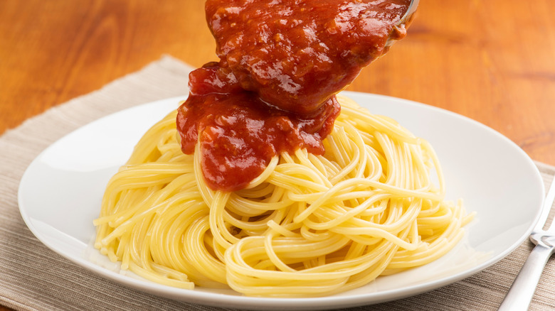 pouring sauce over pasta