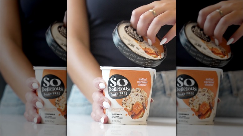 A woman opening a pint of So Delicious Dairy-Free Salted Caramel Cluster