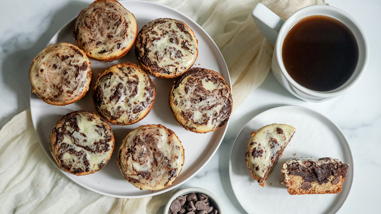 Cheesecake brookie muffins on plate next to cup of coffee