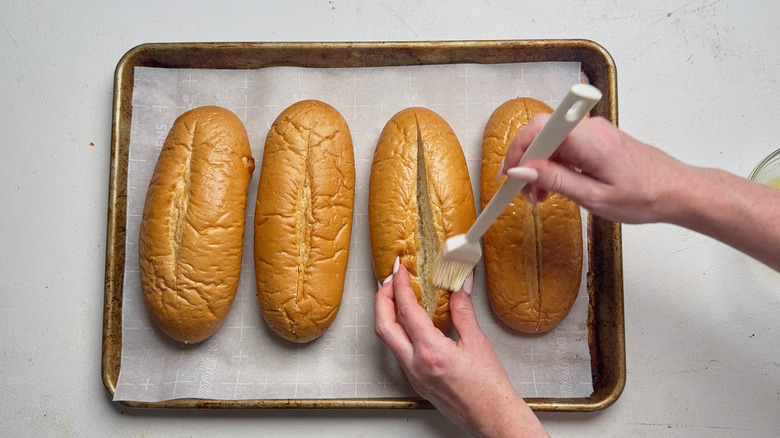 brushing hoagie rolls with butter