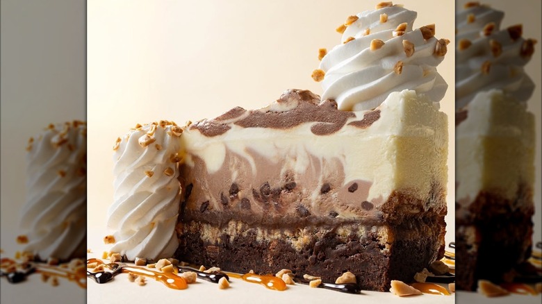 Cheesecake with a brownie crust, topped with whipped cream and nuts.