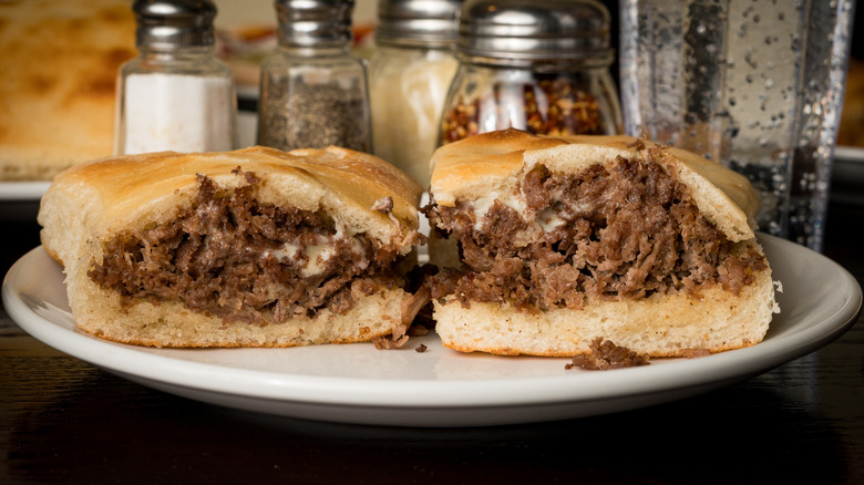 A Philly Cheesesteak sandwich in front of salt and pepper shakers