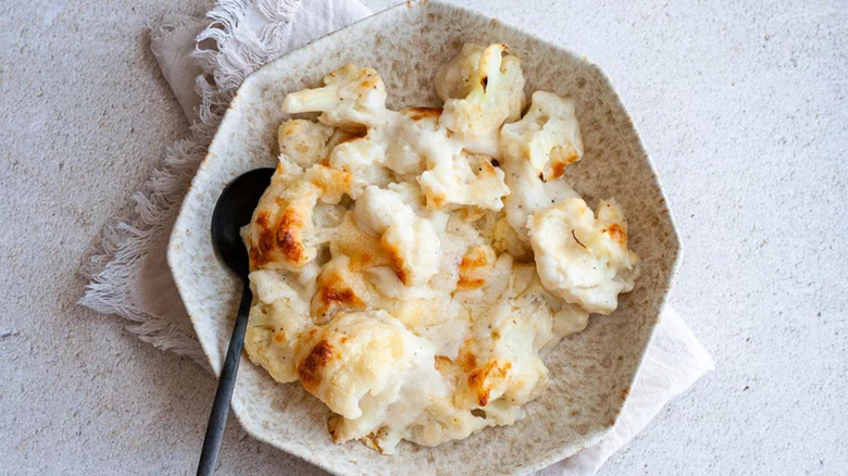 Cauliflower au gratin in a white speckled dish with a spoon