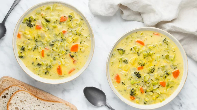 Two bowls of classic broccoli cheddar soup with spoons