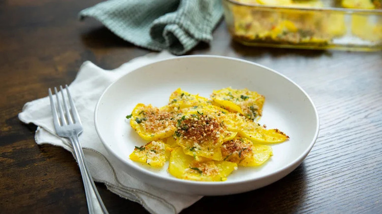 Golden turnip au gratin plated onto a white dish next to a fork