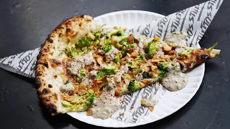 Replica Speedy Romeo NYC roasted broccoli and garlic pizza slice on a paper plate