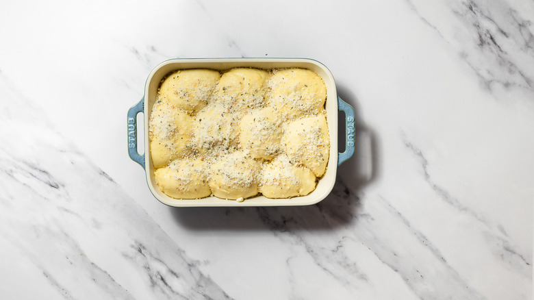 Proofed balls of dough with topping in baking dish