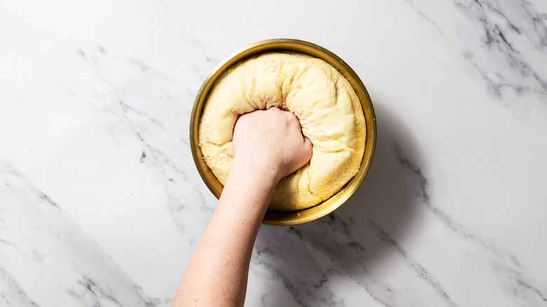 Punching dough in gold bowl