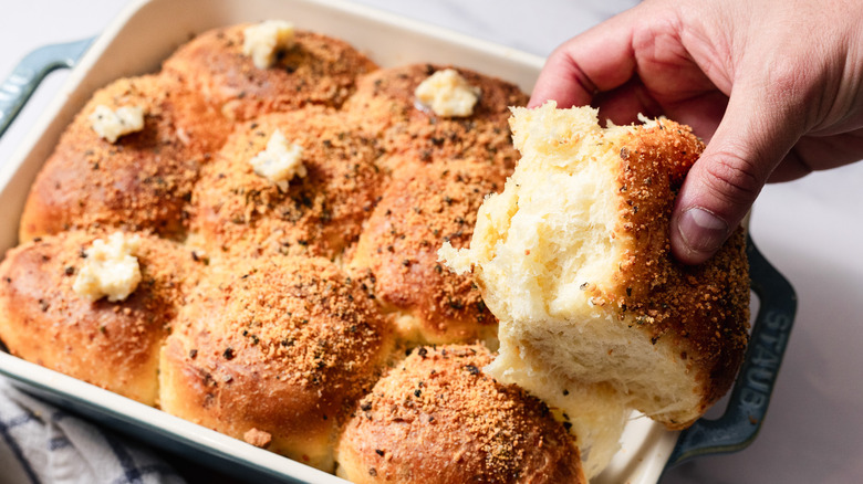 Lifting a garlic dinner roll from casserole dish