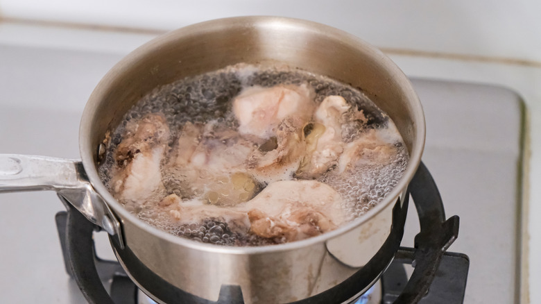 pieces of chicken boiling in stock