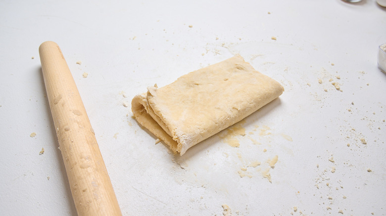 folded dough on a table with a rolling pin