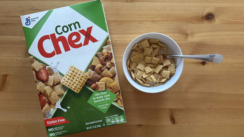 Corn Chex cereals in white bowl on wooden table next to the whole box