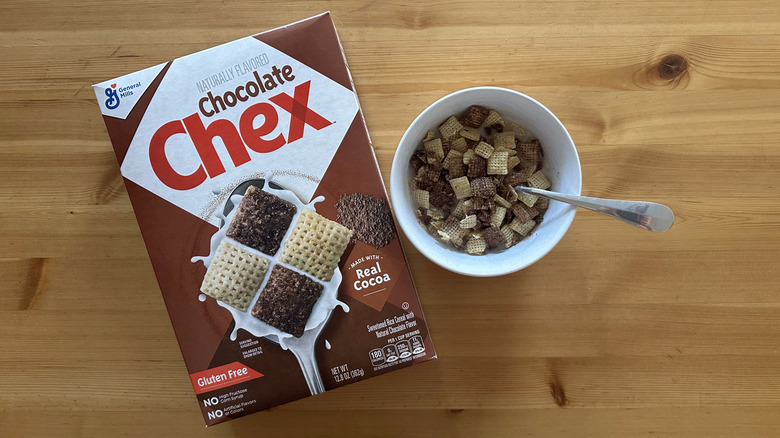 Chocolate Chex in white bowl on wooden table with a box on the side
