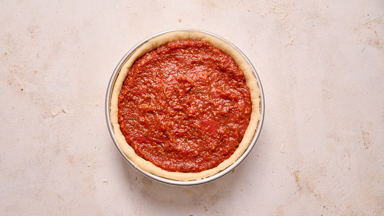 filling pizza crust with tomato sauce