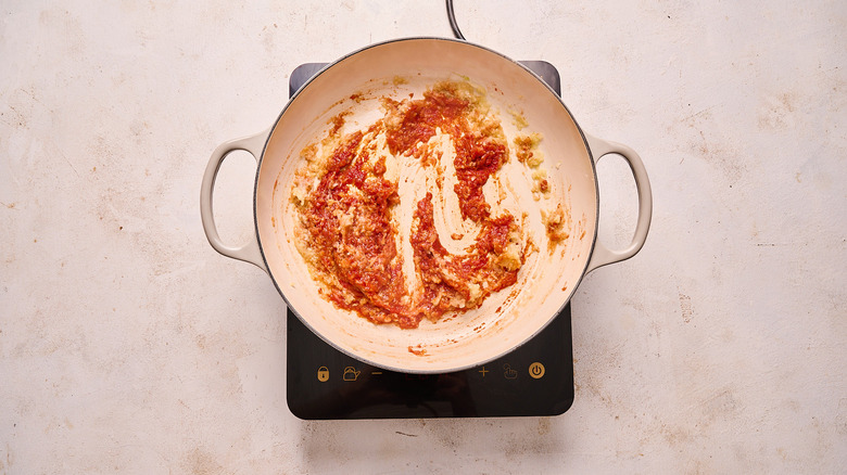 stirring tomato paste into onions