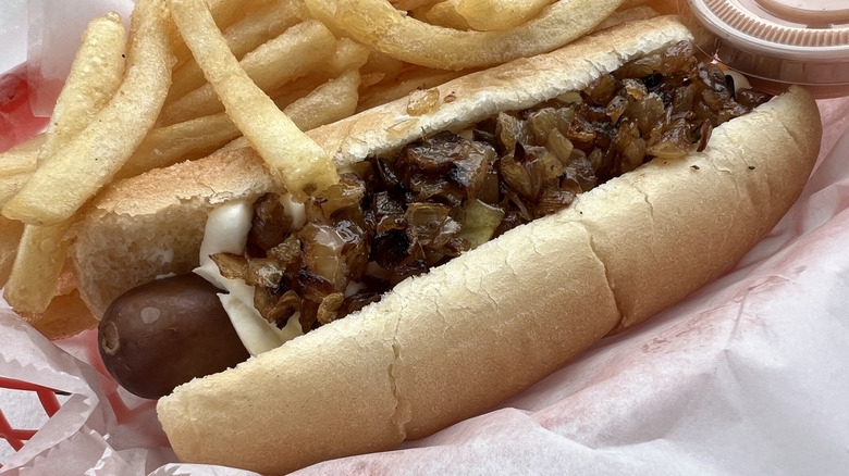 Seattle-style hot dog in basket with fries and sauce cup
