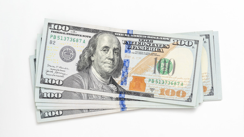 $100 bills in stack on white background