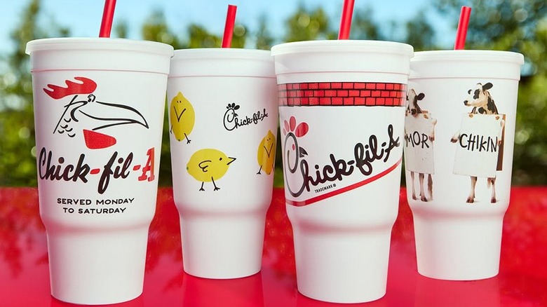 Four to-go cups of Chick-Fil-A lemonade on red table with blurred trees and sky in background