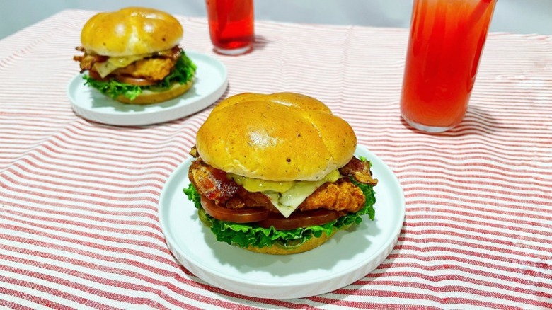 Two of Chick-fil-A's new sandwiches on plates over a striped tablecloth